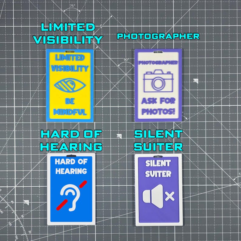 May include: Four rectangular badges with different designs and text. The top left badge says "LIMITED VISIBILITY" with an eye graphic and "BE MINDFUL". The top right badge says "PHOTOGRAPHER" with a camera graphic and "ASK FOR PHOTOS!". The bottom left badge says "HARD OF HEARING" with an ear graphic. The bottom right badge says "SILENT SUITER" with a speaker graphic.