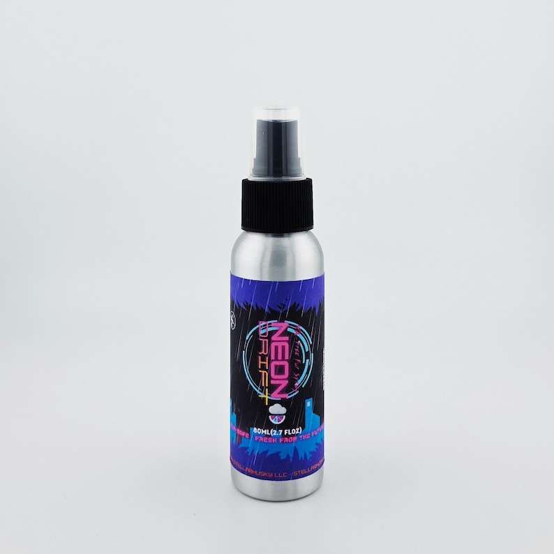 May include: A silver spray bottle with a black cap and a label featuring the text "NEON DRIFT" in pink and blue. The label also includes the text "80ml (2.7 FL OZ)" and a graphic of a cityscape.