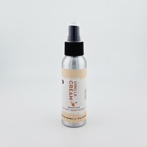 May include: A silver spray bottle with a black nozzle and a label that reads "Vanilla Cream." The label features a light brown design and a small illustration of a bird. The bottle contains 80ml (2.7 fl oz) of product.