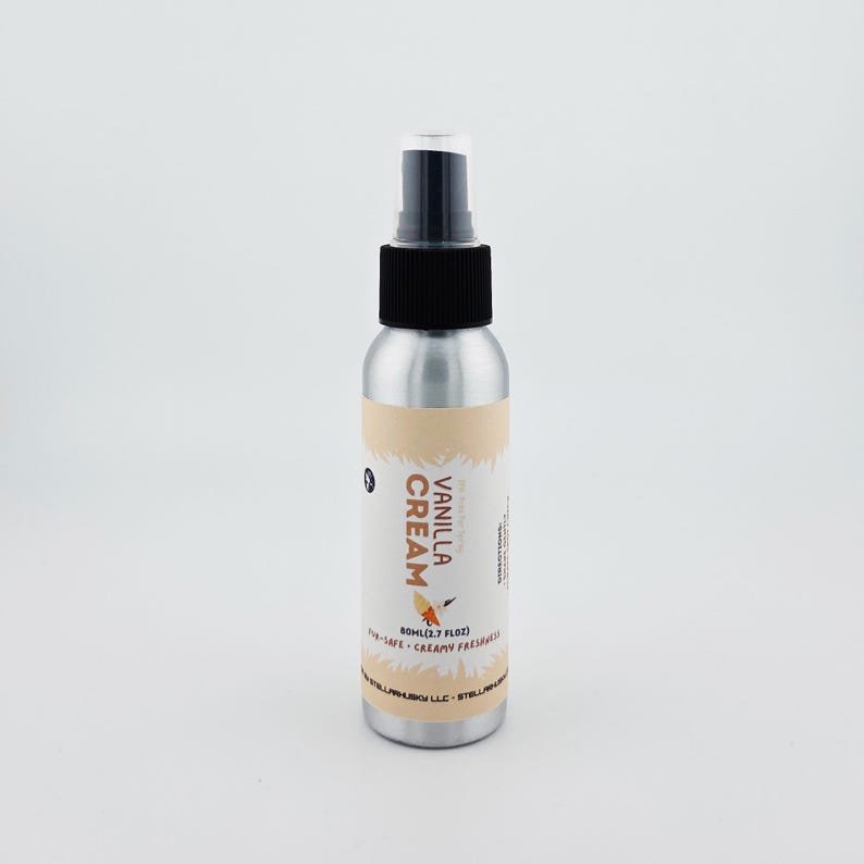 May include: A silver spray bottle with a black nozzle and a label that reads "Vanilla Cream." The label features a light brown design and a small illustration of a bird. The bottle contains 80ml (2.7 fl oz) of product.