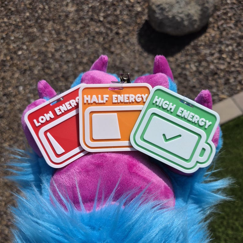 May include: Three energy level tags: red "Low Energy", orange "Half Energy", and green "High Energy". The tags have white borders and battery icons. They are attached to a furry, multi-coloured paw.
