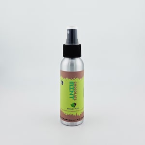 May include: A silver spray bottle with a black cap and a green and brown label. The label reads "Chocolate Mint" and "60ml (2.7 fl oz)." The bottle is designed for liquid.