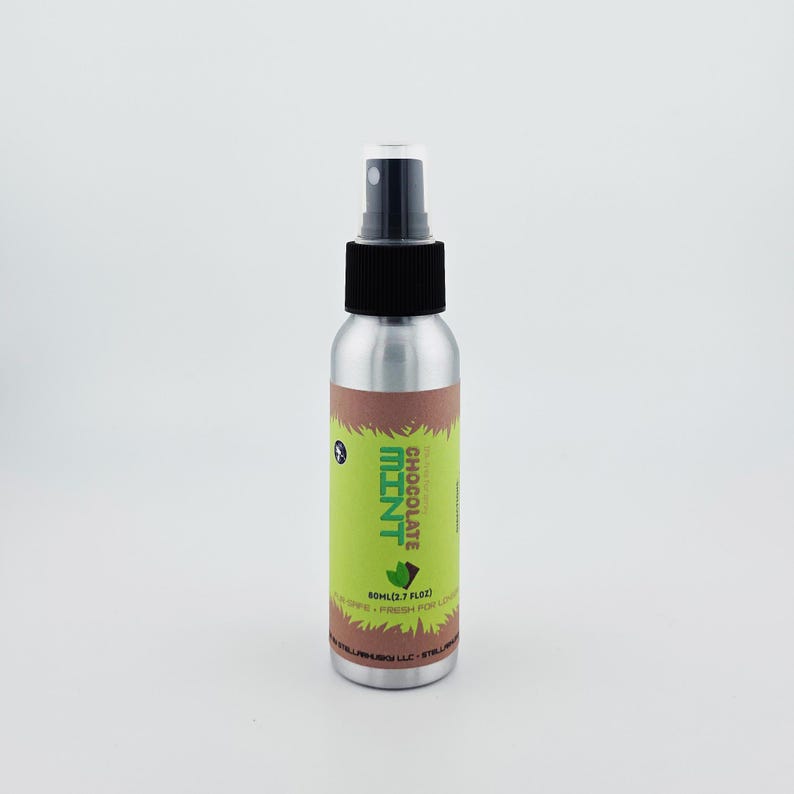 May include: A silver spray bottle with a black cap and a green and brown label. The label reads "Chocolate Mint" and "60ml (2.7 fl oz)." The bottle is designed for liquid.
