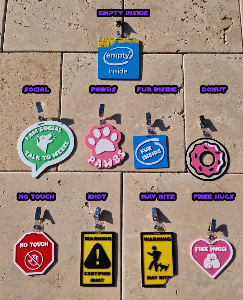 May include: A collection of colorful, novelty tags with various designs and text. Includes a blue tag with "(empty) inside", a pink paw print tag with "PAWBS", and a red "NO TOUCH" tag. Other tags have phrases like "MAY BITE" and "FREE HUGS!"