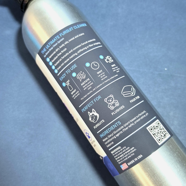 May include: A silver metal spray bottle featuring a dark blue label titled The Ultimate Fursuit Cleaner. The label includes instructions, a list of ingredients, a QR code, and icons representing fursuits, plushies, and faux fur materials.
