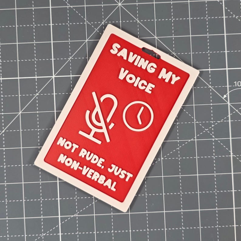 Puede incluir: Una insignia rectangular roja y blanca con el texto "SAVING MY VOICE" y "NOT RUDE, JUST NON-VERBAL". La insignia presenta un micr&oacute;fono tachado y un icono de reloj.