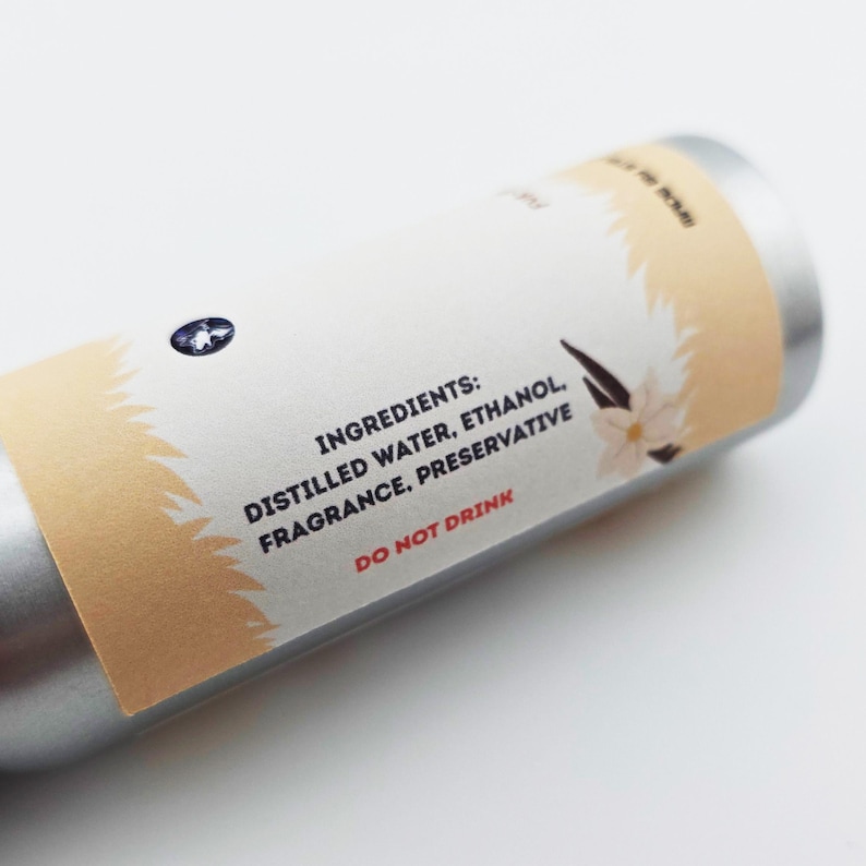 May include: A silver cylindrical container with a label featuring the word "INGREDIENTS:" followed by a list of ingredients. The ingredients listed are distilled water, ethanol, fragrance, and preservative. The label also includes the text "DO NOT DRINK".