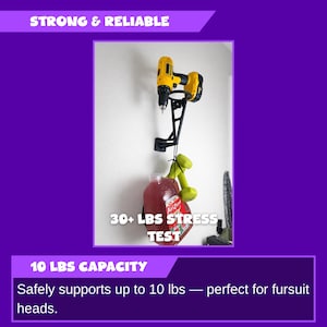 May include: Black metal wall-mounted drill holder with a yellow and black drill attached. A red container and green dumbbells hang from the holder. Text reads "STRONG & RELIABLE" and "30+ LBS STRESS TEST".