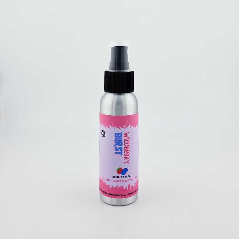 May include: A silver spray bottle with a black cap and a pink and purple label. The label reads "Wildberry Burst" with a strawberry and blueberry graphic. The bottle contains 80ml (2.7 fl oz) of product.