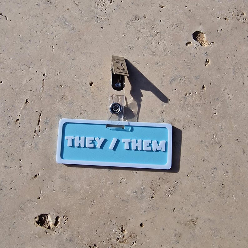 Badge showing they/them on a tile background.
