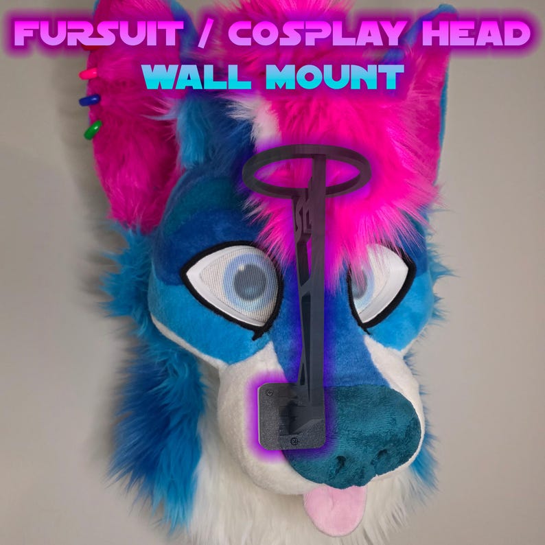 May include: A blue, white, and pink furry cosplay head with a wall mount. The head has large, expressive eyes and a pink tongue. The wall mount is dark gray and designed to hold the head securely. Text at the top reads "FURSUIT / COSPLAY HEAD WALL MOUNT."
