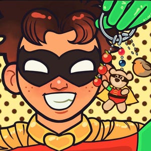 May include: A cartoon illustration of a smiling character wearing a black domino mask and a red and yellow costume with a gold heart-shaped collar. A green-gloved hand holds a silver keychain featuring a small teddy bear, red beads, and a bird.