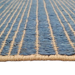 Peut inclure: Gros plan sur un tapis rayé bleu et beige. Le tapis a un aspect texturé et tissé avec des rayures verticales bleues et beiges. Le bord du tapis est de couleur beige.