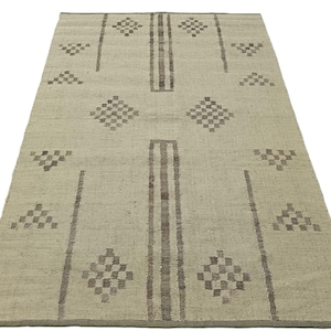 May include: A light beige rug with a geometric pattern in brown. The pattern features diamonds and triangles.