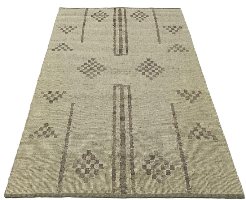 May include: A light beige rug with a geometric pattern in brown. The pattern features diamonds and triangles.