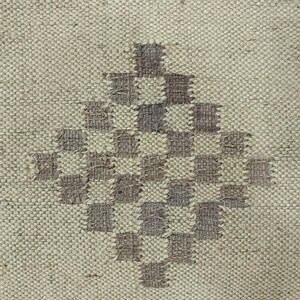 May include: A close-up of a woven rug with a diamond-shaped pattern in shades of brown and beige.