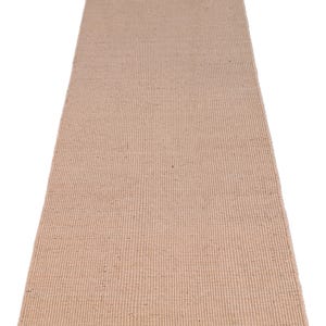 Peut inclure: Un tapis de couloir en fibres naturelles de couleur beige clair. Le tapis a une texture tissée et une forme rectangulaire simple.