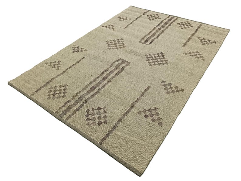 May include: A beige rug with a geometric pattern in brown. The pattern features rows of small squares and diamonds.