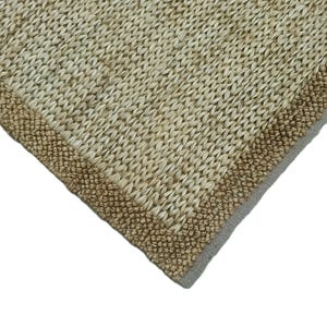 Peut inclure: Gros plan sur un tapis tissé d'aspect naturel et texturé. Le tapis est de couleur beige clair avec une bordure marron plus foncée. Le motif de tissage est visible, créant un aspect tactile. Le coin du tapis est présenté sur fond blanc.