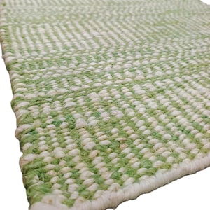 Peut inclure: Gros plan sur un tapis tissé vert et blanc. Le tapis présente une surface texturée avec un motif répétitif de fibres vertes et blanches. Les bords sont finis avec une bordure blanche. Le tapis est fait de fibres naturelles.