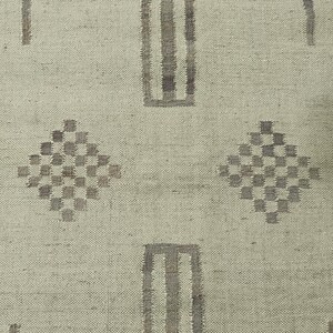 May include: A beige rug with a geometric pattern in brown. The pattern includes vertical stripes and diamond shapes.