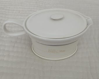 Könnte beinhalten: Eine weiße Keramik-Sauciere mit passendem Deckel und Griff. Die Sauciere hat eine abgerundete Form mit einem Ausguss zum einfachen Ausgießen. Auf der Seite steht "Crock-Pot Gravy Mate".