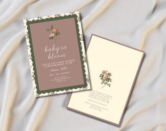 May include: Two rectangular baby shower invitation cards. The left card features a mauve center with a floral illustration, white text reading baby in bloom, and a dark green scalloped border. The right card is cream with a rose illustration.