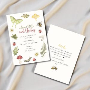 Puede incluir: Dos invitaciones para baby shower con ilustraciones en acuarela de insectos, hojas y setas. La invitación frontal dice "welcome little cuddle bug" con detalles del evento. La parte posterior tiene detalles y una ilustración de abeja.
