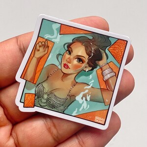 May include: A sticker featuring an illustration of a woman in a pool. The woman has dark hair and is wearing a silver top and bracelets. The background is blue and orange, with the text "HASSAN DRAWS" in the bottom right corner.