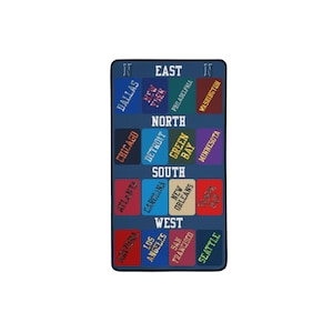 May include: A rectangular, navy blue throw blanket featuring a map design with various city names in different colors. The blanket is divided into sections labeled East, North, South, and West, with city names like Dallas, Chicago, and Seattle.