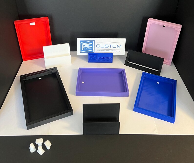 May include: Assortment of acrylic display stands in various colors, including black, white, red, pink, purple, and blue. The stands are designed to hold business cards, photos, or other small items. The stands are made of clear acrylic and have a modern, minimalist design. The stands are also available in a variety of sizes to accommodate different needs.