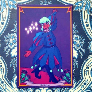 May include: A tarot card illustration featuring a figure in a blue and red outfit with a white collar, holding a wand. The card has a purple background with the word "I" at the top and "The Magician" at the bottom.