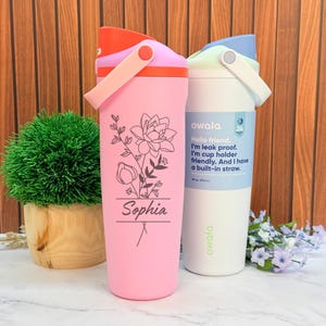 May include: Two insulated water bottles. One is pink with a floral design and the name "Sophia." The other is white with a blue lid and a label that reads "Hello friend. I'm leak proof. I'm cup holder friendly. And I have a built-in straw."