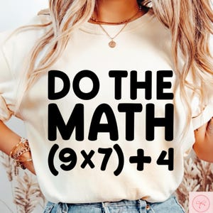 May include: Cream-colored sweatshirt with the phrase "DO THE MATH" in bold black letters. Below the text is the equation (9x7)+4. The sweatshirt is a casual style, suitable for everyday wear.