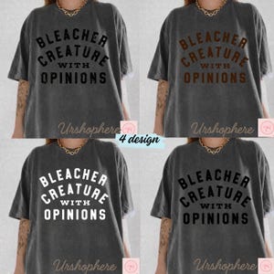 May include: Four gray t-shirts with the text "BLEACHER CREATURE WITH OPINIONS" in different colors. The shirts have short sleeves and a relaxed fit. The brand name "Urshophere" is at the bottom of each shirt.