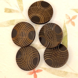 May include: Five dark brown, circular buttons with a unique design. Each button features a central dark circle with a lighter brown, wave-like pattern radiating outwards. The buttons are arranged on a patterned background.