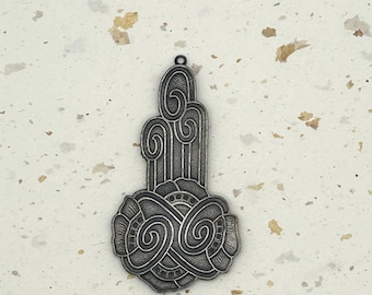 Puede incluir: Colgante plateado con diseño Art Déco. El colgante presenta una base floral estilizada con detalles en espiral y una sección superior alargada con líneas verticales y elementos curvos. Un pequeño lazo en la parte superior para colgar.