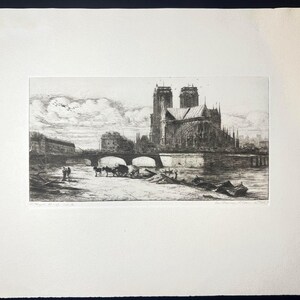 May include: A black and white etching of Notre Dame Cathedral in Paris, France, with a bridge and figures in the foreground. The artwork is framed in a white mat.