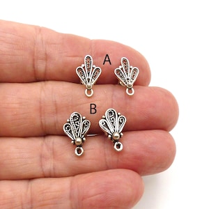 May include: Close-up of two pairs of silver-toned filigree fan-shaped earring components. Each component has a small loop at the bottom and a decorative bead. The components are labeled A and B.