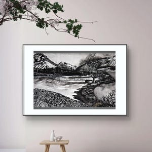 Könnte beinhalten: Schwarz-Weiß-Landschaftskunst-Druck in einem schwarzen Rahmen. Das Kunstwerk zeigt eine Bergkette, einen Fluss und Bäume. Der Druck wird an einer weißen Wand mit einem kleinen Holztisch und dekorativen Gegenständen davor ausgestellt.