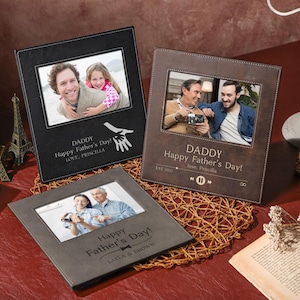 Puede incluir: Tres marcos de fotos de cuero marrón con un borde cosido. Cada marco tiene una foto diferente y un mensaje personalizado. Los mensajes incluyen "Daddy Happy Father's Day! Love, Priscilla", "Daddy Happy Father's Day! Love, Priscilla", y "Happy Father's Day! Layla & Brown".