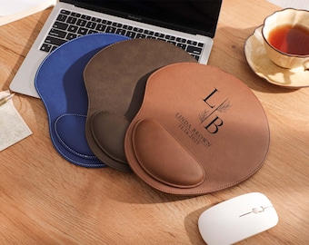 May include: Three ergonomic mouse pads in blue, brown, and tan, with a laptop and a cup of tea in the background. The tan pad has the initials "LB" and the name "LINDA BROWN" with the date "11.16.2025" printed on it. A white mouse is also visible.