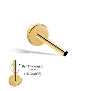 Könnte beinhalten: Goldfarbener Ohrring mit flacher Rückseite und geradem Steg. Der Ohrring hat eine kreisförmige, flache Vorderseite mit einer dünnen, dunklen Linie am Rand. Der Steg ist 1 mm dick (18 Gauge).