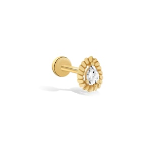 May include: Gold pear-shaped stud earring with a clear gemstone surrounded by a textured halo.