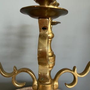 Puede incluir: Un candelabro de lat&oacute;n con tres brazos, con una columna central y brazos curvos decorativos. El candelabro tiene un acabado pulido, que refleja la luz, y est&aacute; dise&ntilde;ado para sostener velas. El dise&ntilde;o es ornamentado y vintage.