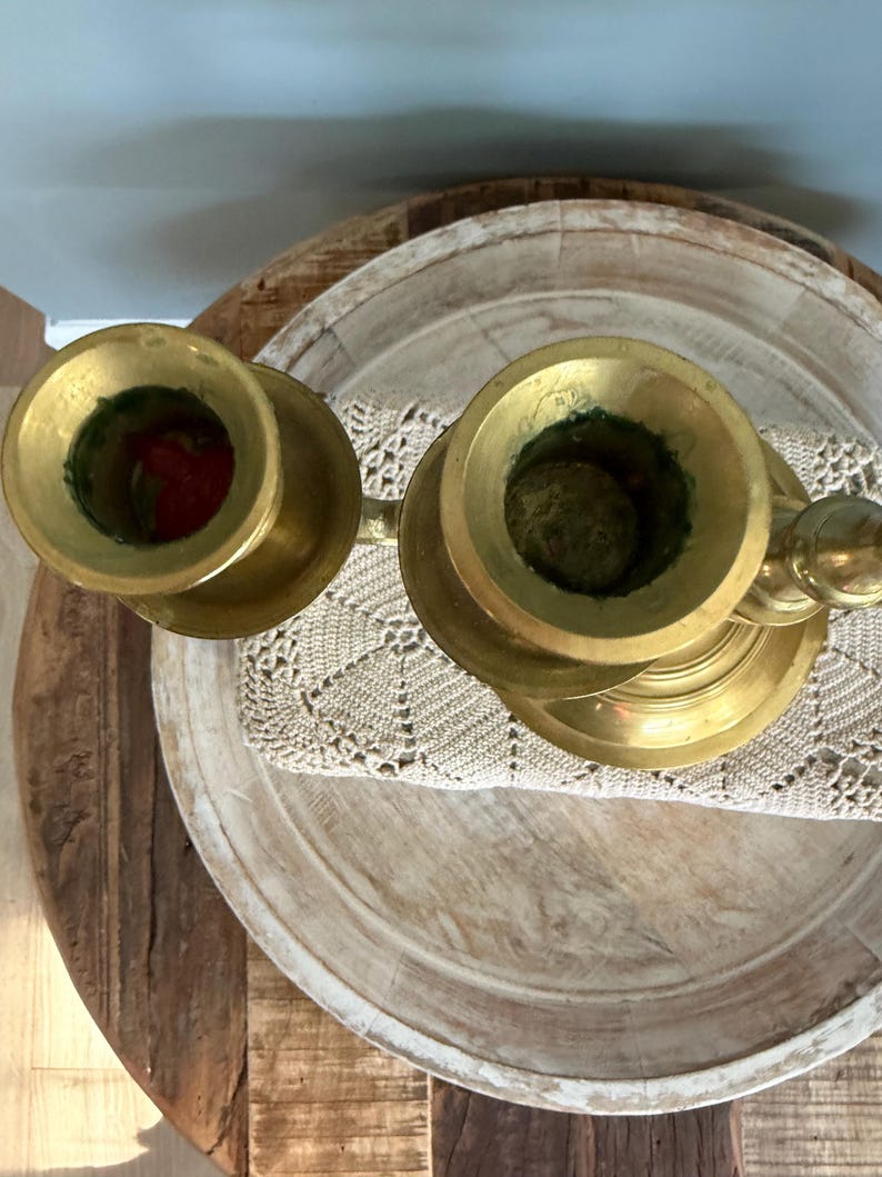 Puede incluir: Dos candelabros antiguos de lat&oacute;n con un acabado deslustrado. Los candelabros est&aacute;n colocados sobre una bandeja de madera con un tapete de ganchillo. Los candelabros tienen un dise&ntilde;o cl&aacute;sico, con una base ancha y una parte superior en forma de copa.