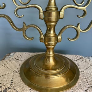 Puede incluir: Un candelabro de lat&oacute;n con m&uacute;ltiples brazos curvos y una base redonda. El candelabro tiene un dise&ntilde;o ornamentado con remolinos decorativos y un acabado pulido. La base tiene aproximadamente 15 cm de di&aacute;metro.