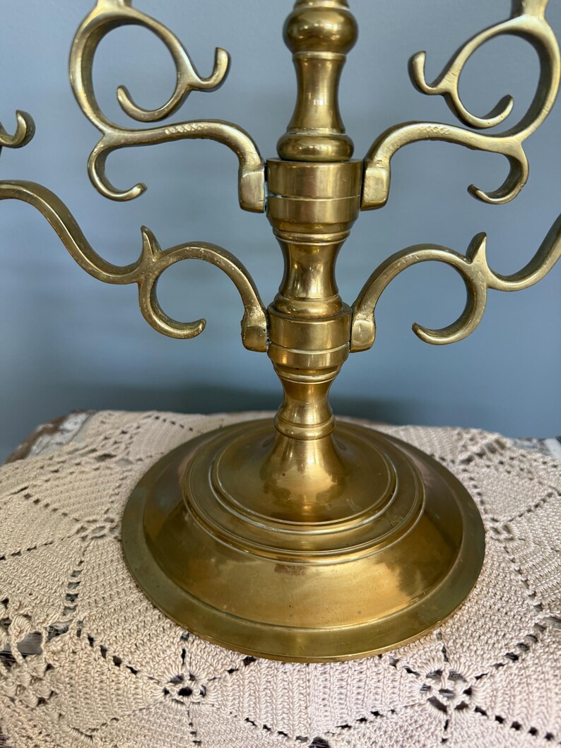 Puede incluir: Un candelabro de lat&oacute;n con m&uacute;ltiples brazos curvos y una base redonda. El candelabro tiene un dise&ntilde;o ornamentado con remolinos decorativos y un acabado pulido. La base tiene aproximadamente 15 cm de di&aacute;metro.