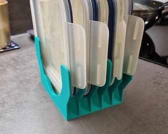 Może przedstawiać: Turkusowy plastikowy organizer na pojemniki, w którym znajduje się kilka przezroczystych pojemników do przechowywania żywności z niebieskimi i białymi akcentami. Organizer ma szczelinową konstrukcję, która utrzymuje pojemniki w pozycji pionowej.