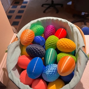 May include: A wicker basket filled with colorful, textured Easter eggs. The eggs are various shades of orange, green, blue, red, and yellow. Some eggs have a smooth surface, while others have a textured, patterned design.